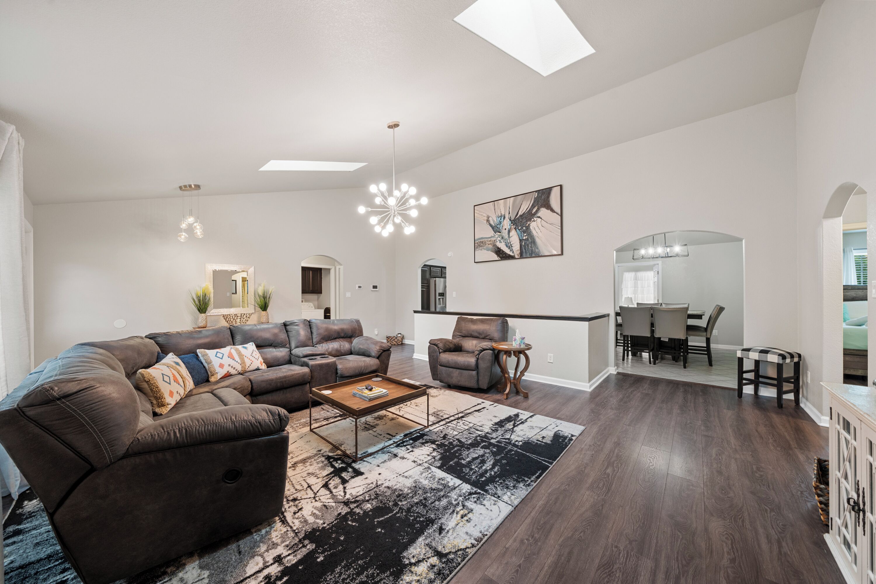 A spacious living room with a sectional sofa, a coffee table, and a dining area with a table and chairs.