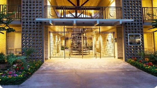 Un hotel con fachada de madera, una entrada central con diseño geométrico y un balcón con barandilla.
