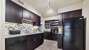 Una cocina moderna con armarios oscuros, un refrigerador negro y un salpicadero de azulejos.