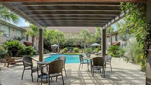 Un espacio exterior cubierto con piscina, sillas y sombrillas.