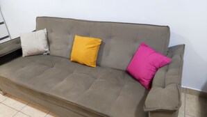 A grey sofa with three cushions in different colors. - Renomado Apartamento em Curitiba  (Curitiba)