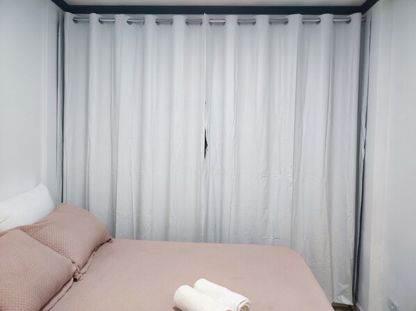 A bedroom with a bed, pillows, and a rolled towel.