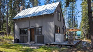 A rustic cabin with a metal roof, a front door, and a small porch with a bench.
