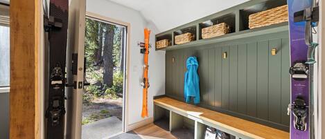 Una cabaña para esquiar con un banco de madera, estantes de almacenamiento y esquíes.