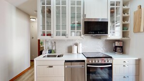 Una cocina moderna con armarios blancos, lavavajillas de acero inoxidable y horno.