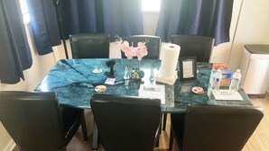 Un espace repas comprenant une table en marbre, des chaises noires, un vase à fleurs, un rouleau de mouchoirs, un menu et des bouteilles d’eau.