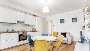 Een moderne keuken met witte kasten, een fornuis en een eethoek met een ronde tafel en stoelen.