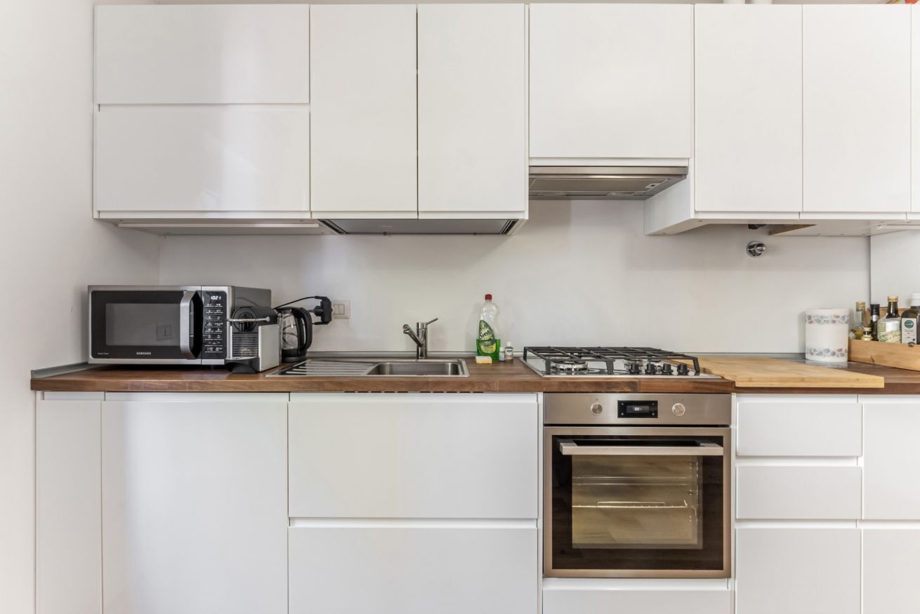 A kitchen with white cabinets, a microwave, a stove, and an oven.