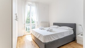 Een slaapkamer met een bed, nachtkastje, lamp en uitzicht op de omgeving.