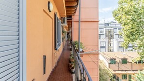 Een smal balkon met betegelde vloer, plantenpotten en een metalen hekwerk.