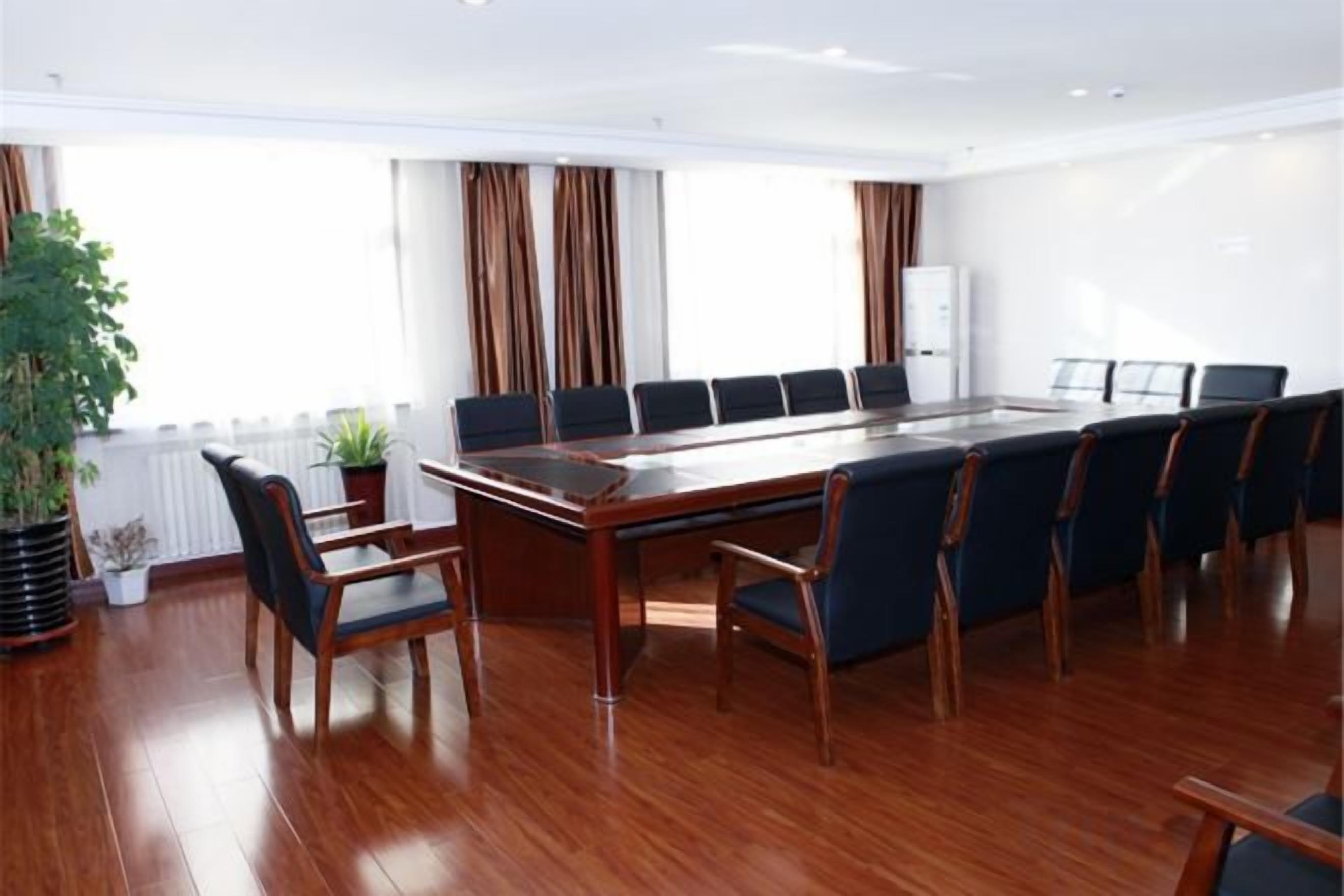 Un salón de conferencias con una larga mesa, varias sillas y una planta en maceta.