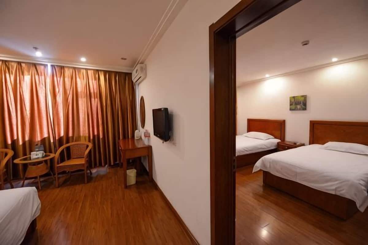 A hotel room with two beds, a desk with a chair, a TV, and a window with curtains.