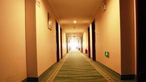A hotel hallway with a carpeted floor, doors on both sides, and a light at the end. - Runyang Jiayue Hotel (Dalian Jinzhou Railway Station) (Dalian)