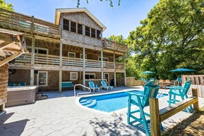 A two-story wooden building with a swimming pool, outdoor seating, and a covered patio area. - Big Guppy: Pool, Elevator, Hot Tub, Dog-Friendly (Duck)