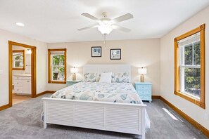 A bedroom with a bed, two bedside tables with lamps, a ceiling fan, a window, and a door leading to another room. - Big Guppy: Pool, Elevator, Hot Tub, Dog-Friendly (Duck)