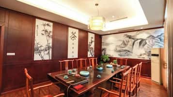 A traditional dining room with a long table, wooden chairs, and artwork on the walls.