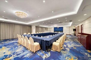 Un salón de conferencias con una mesa larga, sillas y suelo alfombrado.