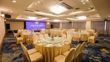Une salle de conférence équipée de tables rondes, de chaises et d’un grand écran.