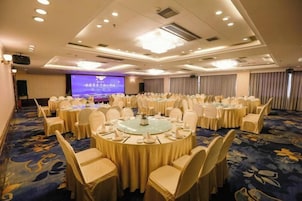 Un salón de conferencias con mesas redondas, sillas y una pantalla grande.