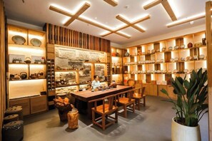 A traditional interior with wooden shelves displaying pottery, a central dining table, and chairs. - Zhongwei Sunny Hotel (Jinyun)