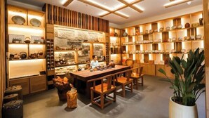 A traditional Japanese-style room with wooden furniture, a central table, and shelves displaying pottery and ceramics. - Zhongwei Sunny Hotel (Jinyun)