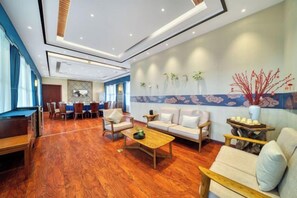 A hotel lobby with a wooden floor, a sofa set, a coffee table, and a dining area with chairs and a table. - Zhongwei Sunny Hotel (Jinyun)