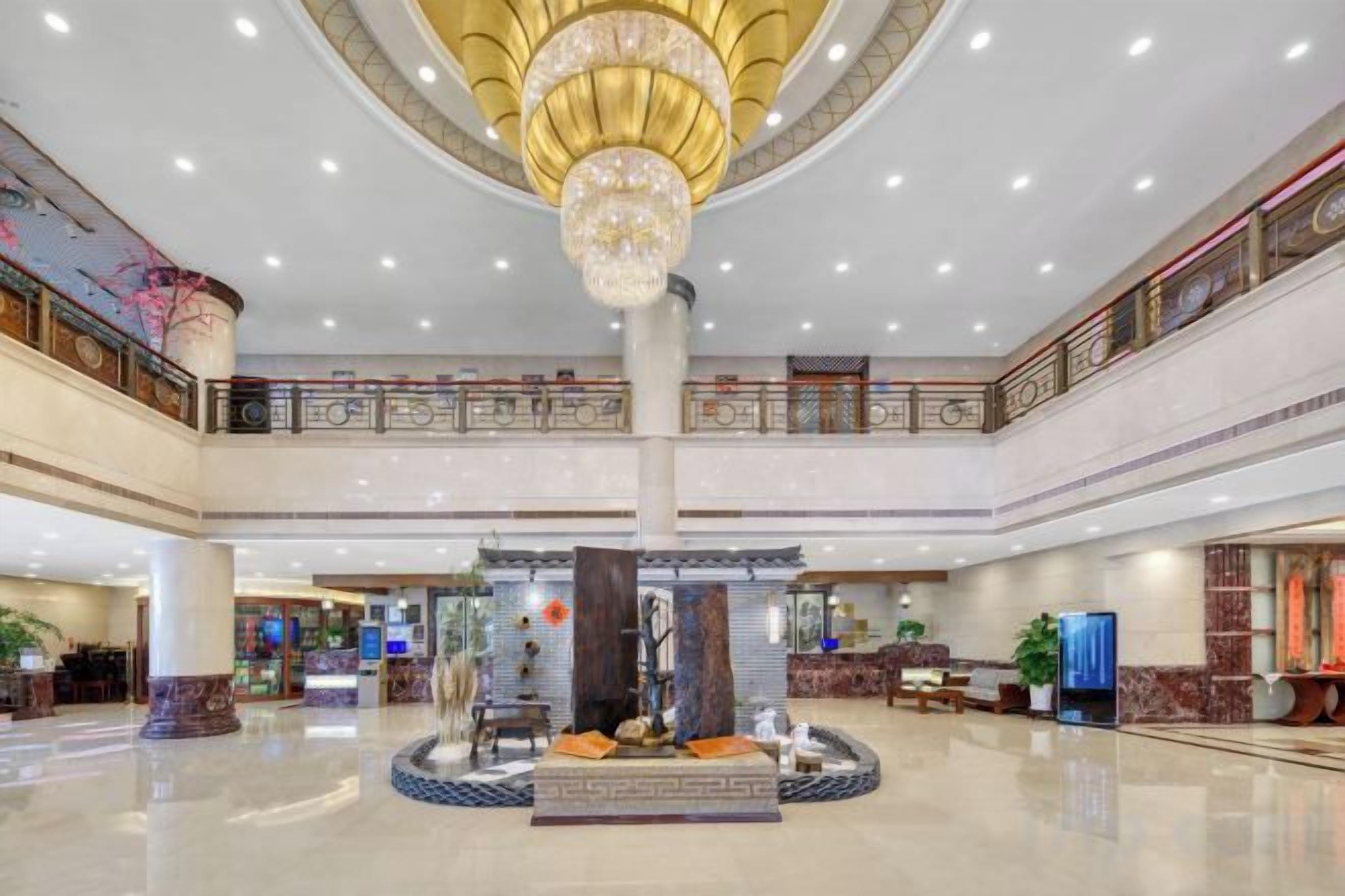 A spacious lobby with a central fountain, multiple levels, and a grand chandelier.