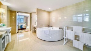A modern bathroom with a large bathtub, a vanity with a mirror, and a shower area. - Zhongwei Sunny Hotel (Jinyun)