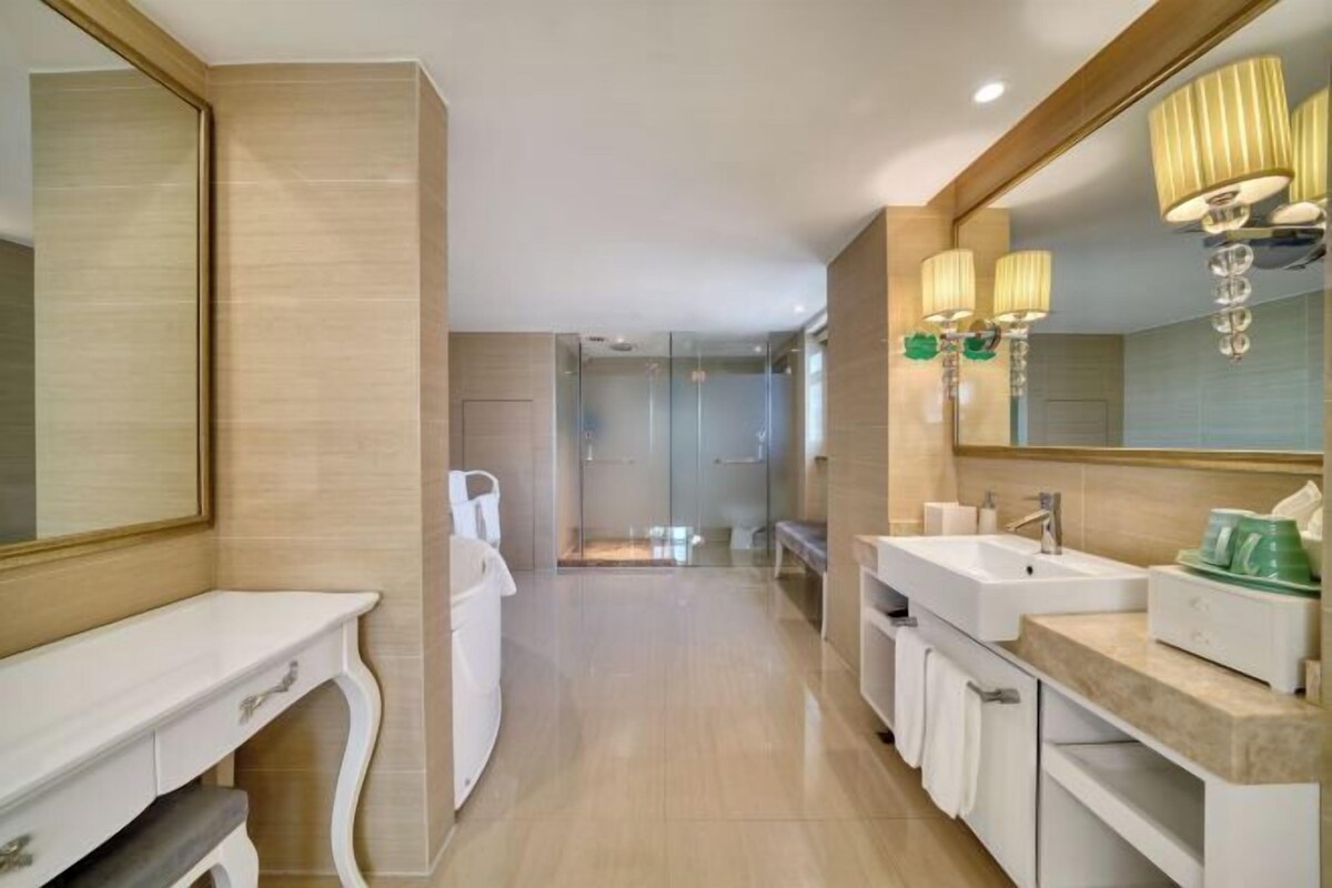 A modern bathroom with a large mirror, two sinks, and a shower area.
