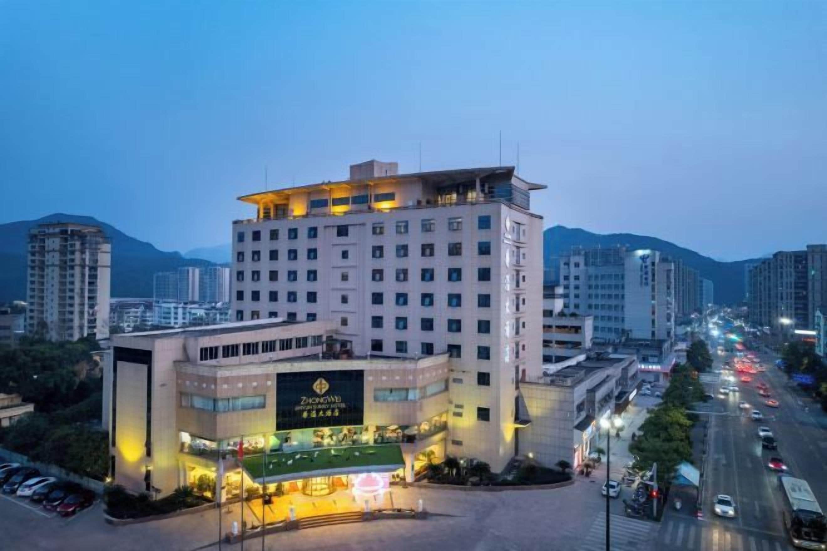 A multi-story hotel with a prominent entrance and a parking area in front.