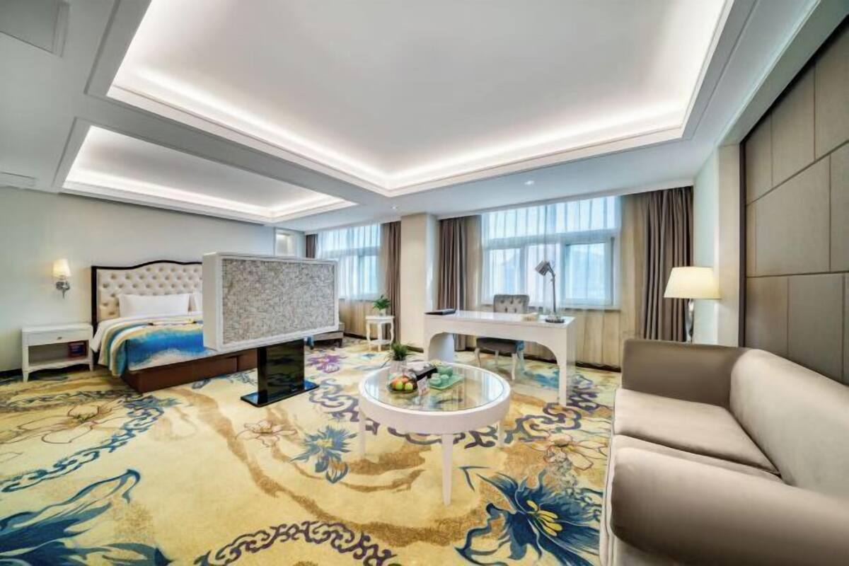 A hotel room with a bed, a desk, a round coffee table, and a sofa.