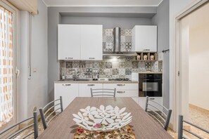 A modern kitchen with white cabinets, a gas stove, and a stainless steel range hood.