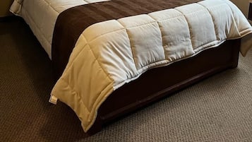 A neatly made bed with a wooden headboard, a bedside lamp, and a framed picture on the wall.