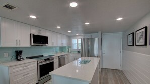 Una cocina moderna con armarios blancos, electrodomésticos de acero inoxidable y una isla central.