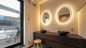A modern bathroom with two oval mirrors, a dark wooden vanity, and a round stool. - Bettei Fujiya (Hatsukaichi)