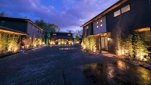 A modern building with a gravel driveway and illuminated plants. - Bettei Fujiya (Hatsukaichi)