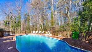A rectangular swimming pool with a wooden deck, surrounded by a wooden fence and trees. - Designer Home - Pool - Billiards - Home Office (Cary)