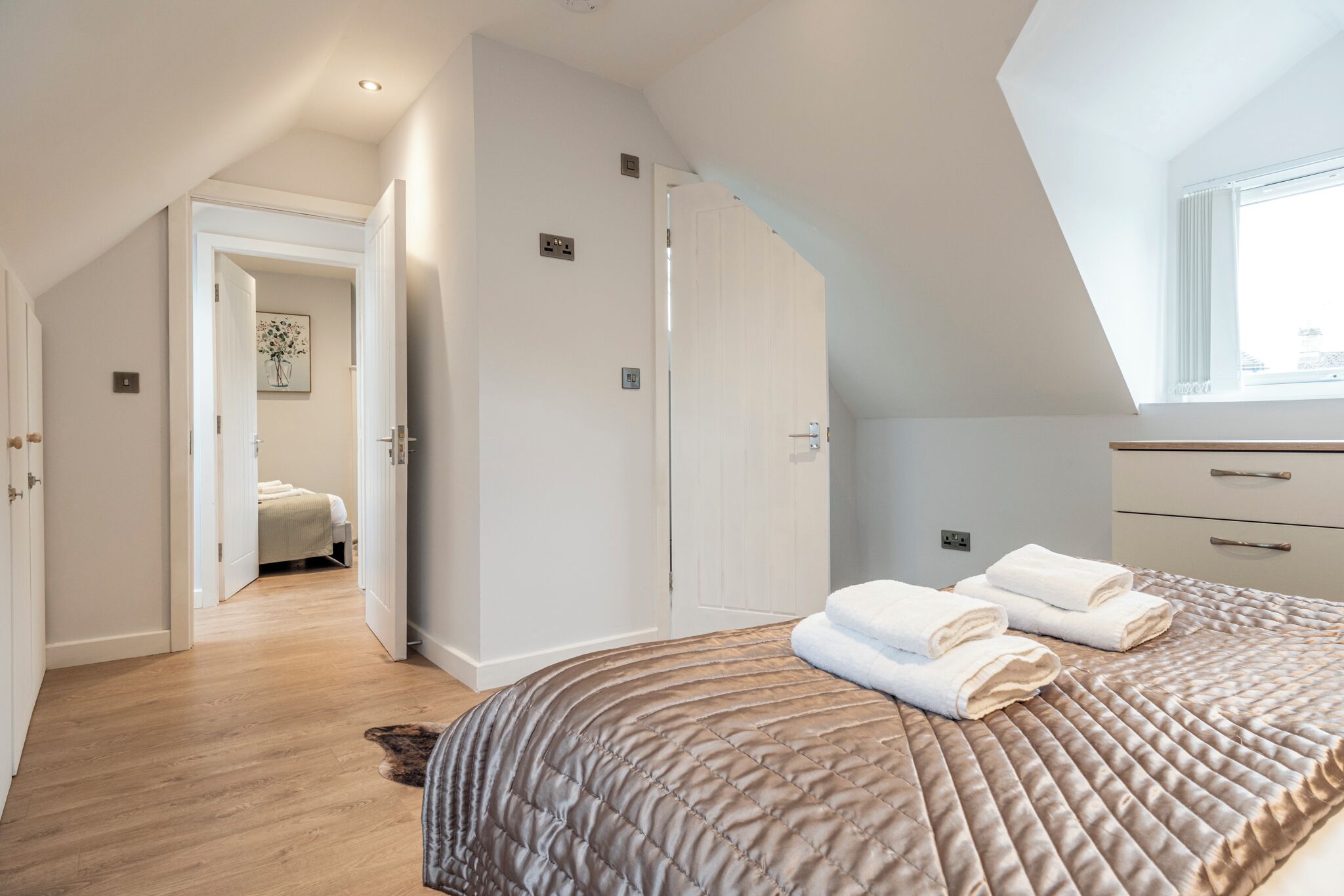 A bedroom with a large bed, a window, and a walk-in closet.