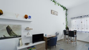 Ein modernes Wohnzimmer mit Flachbildfernseher, Schreibtisch und Essbereich mit Stühlen.