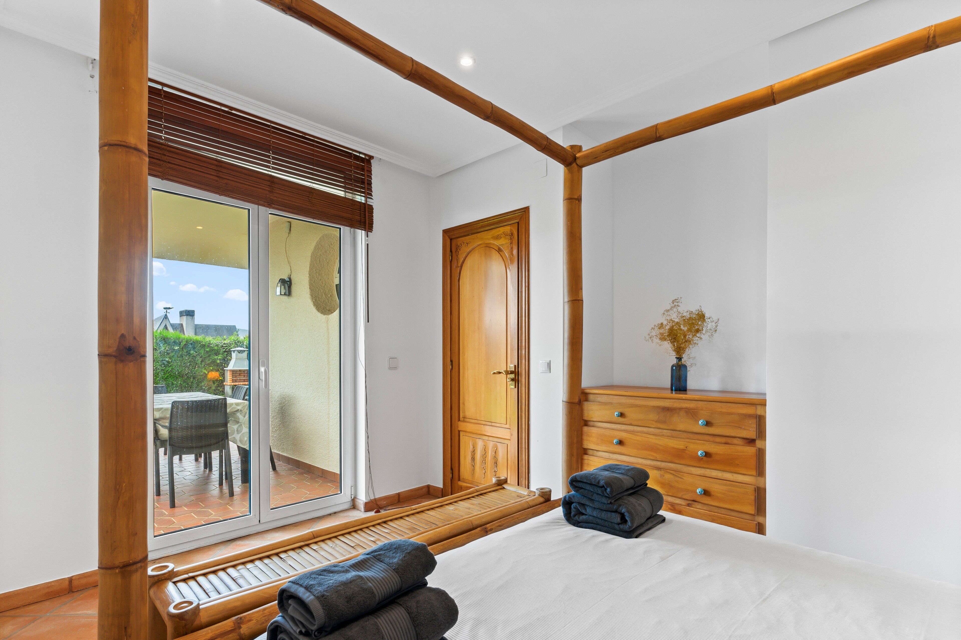 Une chambre à coucher comprenant un lit, une armoire en bois et une porte-fenêtre coulissante donnant sur un patio.
