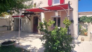 Une maison avec un auvent rouge, une porte et une fenêtre avec des volets.