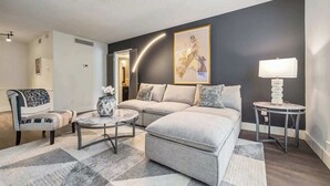 A modern living room with a sofa, armchair, coffee table, and a lamp.