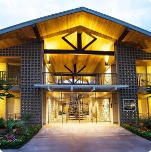 A modern building with a wooden facade, a central entrance with a geometric design, and a balcony with a railing. - Serena Luxe | Walk to Galleria | Holiday-Ready (Houston)