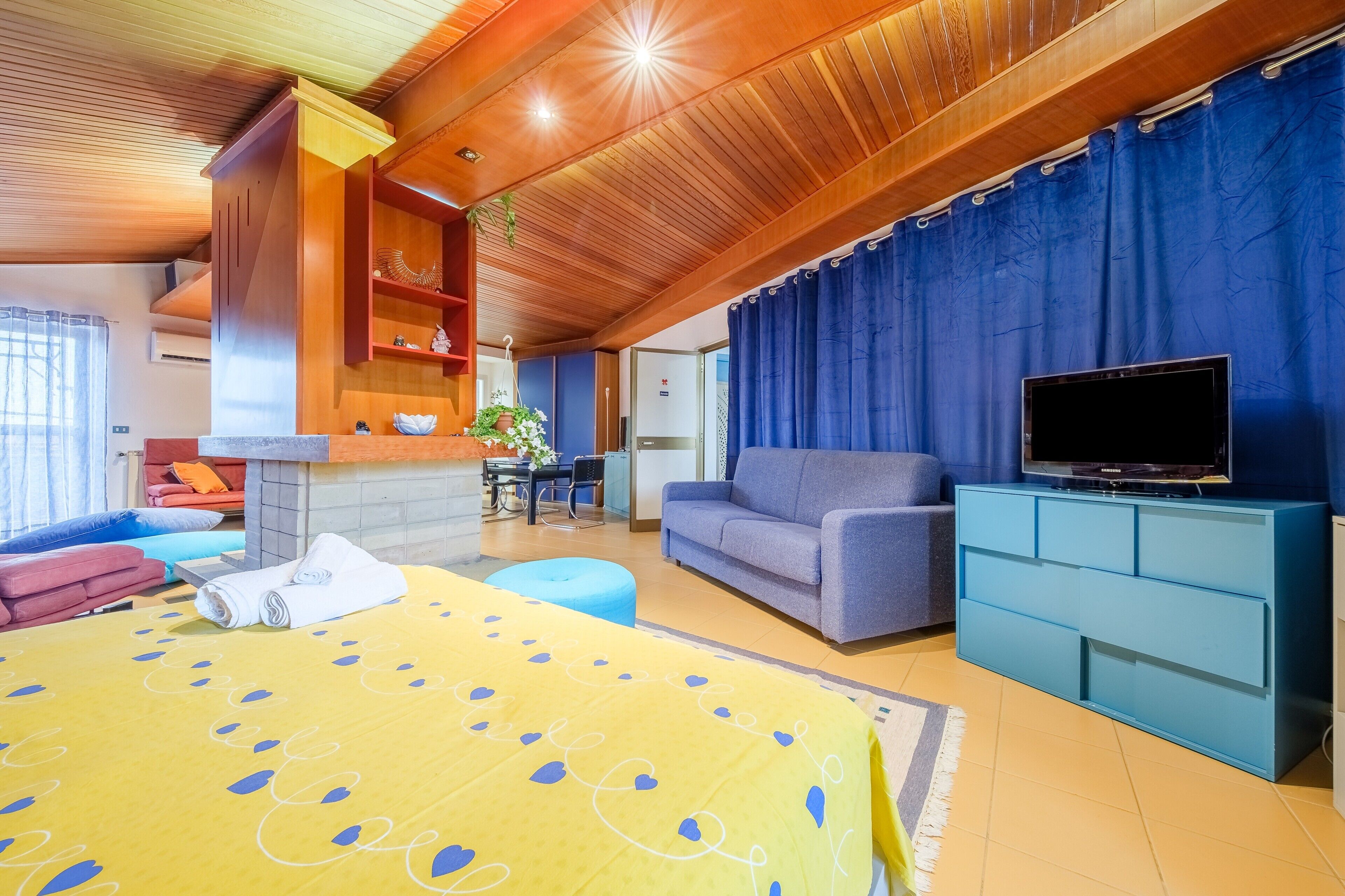 Ein Zimmer mit einem Bett, einer Couch, einem Fernseher und einer Essecke.