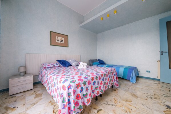 Un dormitorio con dos camas, una mesita de noche, un cuadro enmarcado en la pared y una puerta.