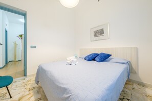 Una habitación de hotel con una cama, un cuadro en la pared y un baño visible a través de una puerta abierta.
