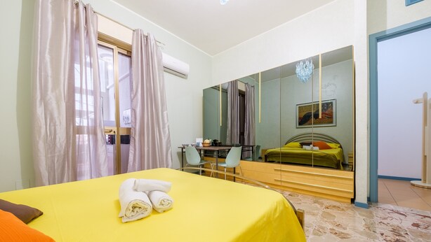Ein Hotelzimmer mit Bett, Schreibtisch, Stuhl, Spiegel und Blick ins Freie.