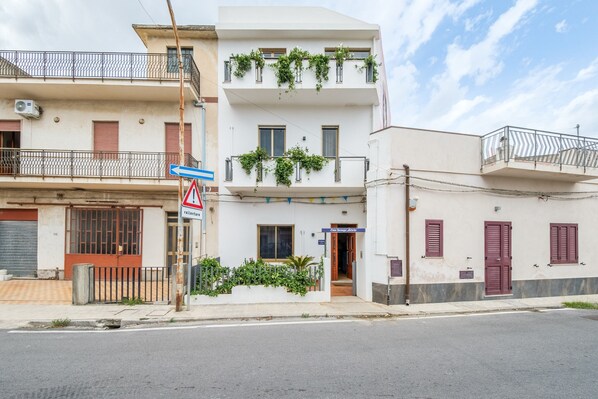 Un edificio de varios pisos con balcones, una entrada visible y una señal de calle.