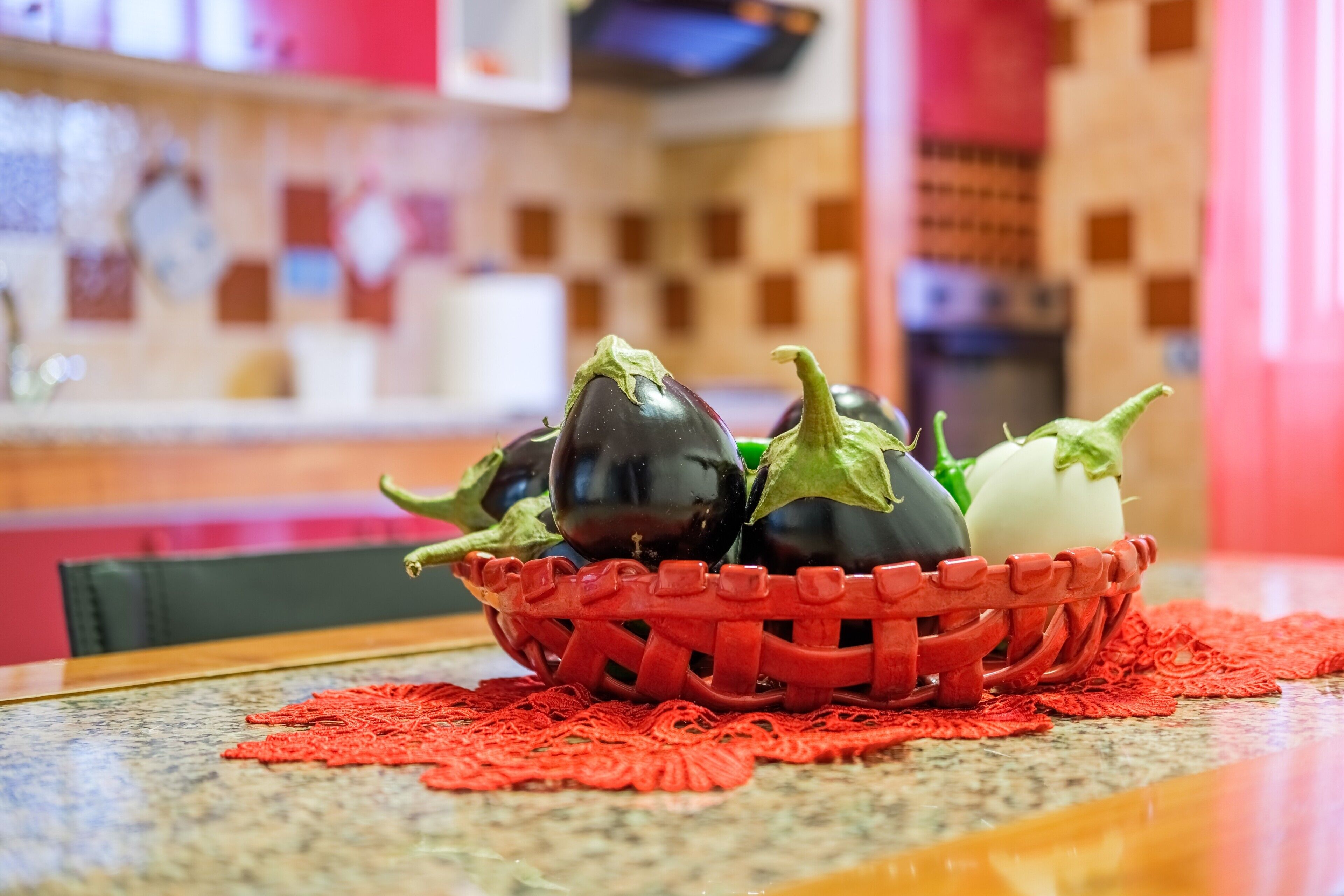 A basket of vegetables on a table with a red doily.