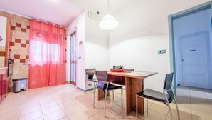 A dining area with a wooden table, chairs, and a basket of fruit.